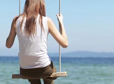 Back of Woman Sitting on Swing by Sea
